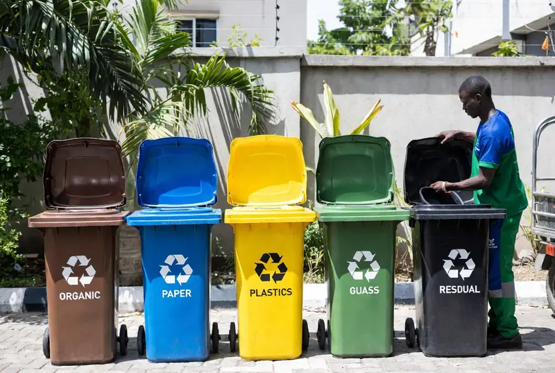 Colour-coded segregation bins - organic, paper, plastics, glass and residual - beside an operator in uniform